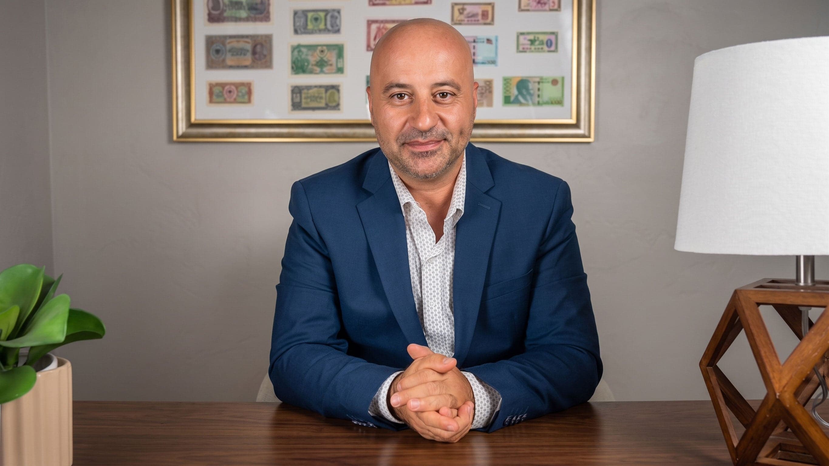 Ardi Kotoni seated at his desk in a navy blazer